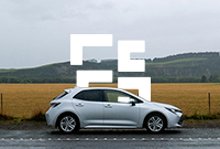 Silver car in front of field