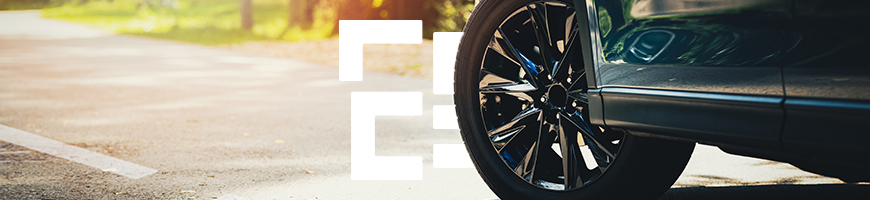 Close-up of a black car's front wheel on a sunny road