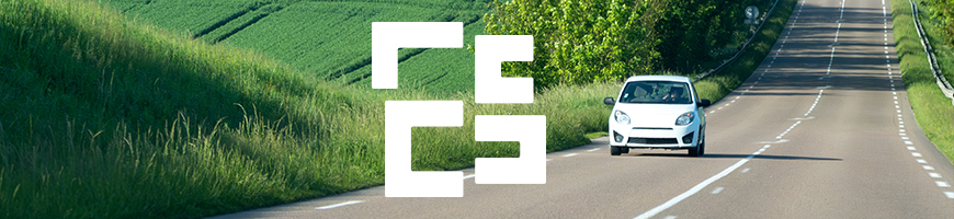 A small white car drives along a picturesque road surrounded by greenery in the Grand Est region of France