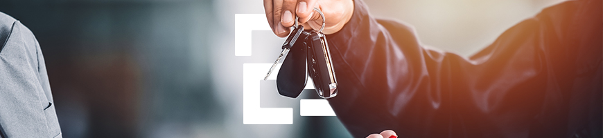 A hand gives car keys to the open hand of the person renting a car.