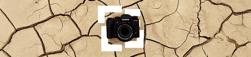 Black DSLR laying on sand coloured cracked ground