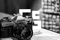 Black and white photo of a camera balanced on a table