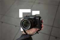 Person holding a camera in front of a pavement