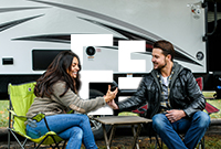 Couple sitting in front of caravan in their camping chairs