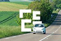 A small white car drives along a picturesque road surrounded by greenery in the Grand Est region of France