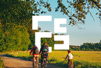 Family of three on bikes cycling on a path through the sunny countryside