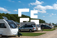 A group of caravans parked on a grassy field under a blue sky