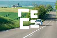 A small white car drives along a picturesque road surrounded by greenery in the Grand Est region of France