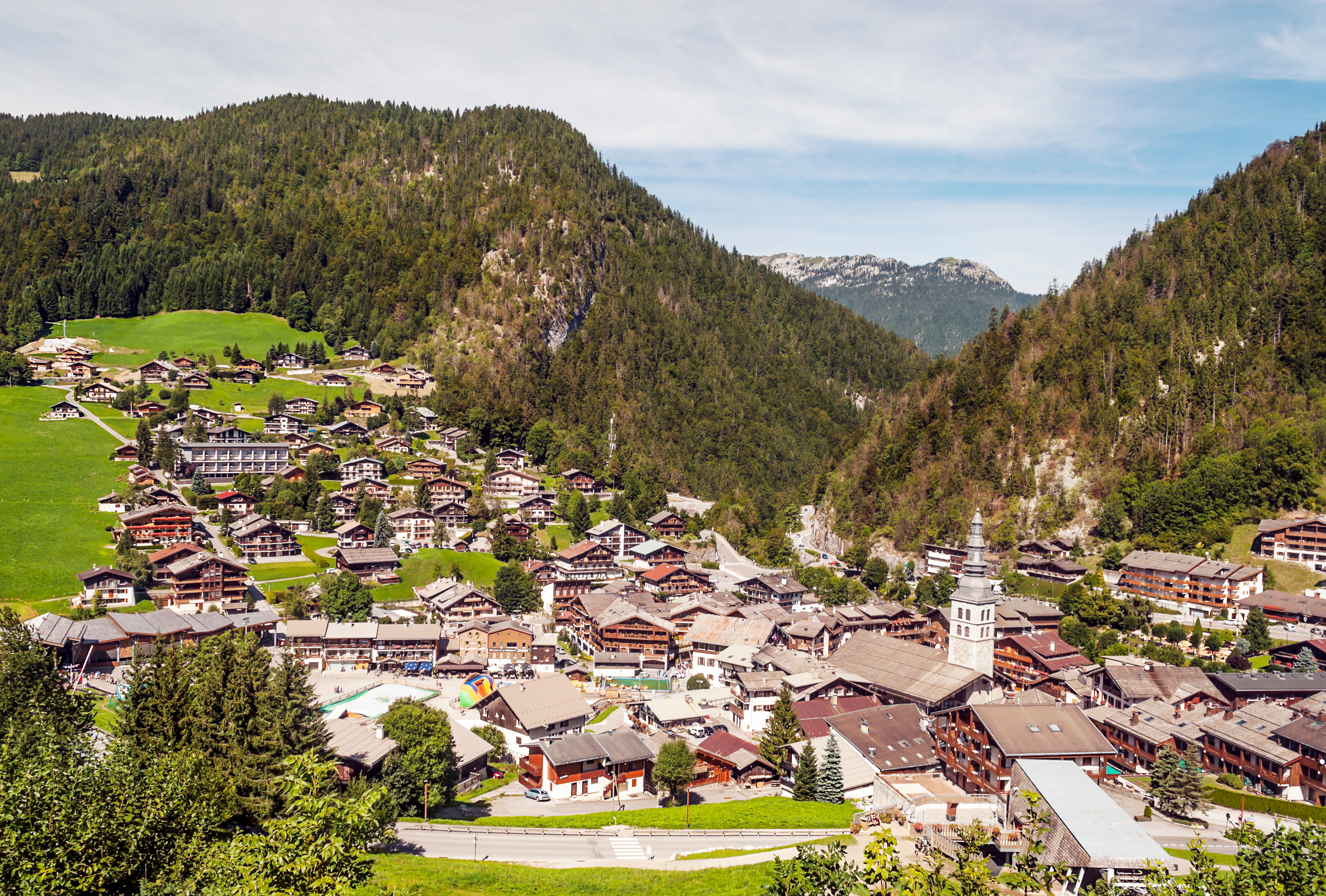 The alpine village of Megève featuring clustered wooden houses and a church steeple surrounded by forested hills