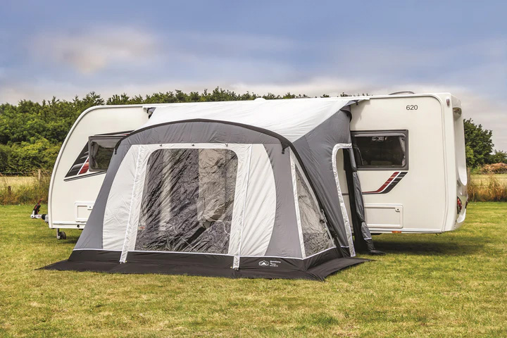 Sunncamp Swift 220 caravan awning attached to side of touring caravan parked in a green grassy field