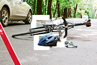 A broken down bicycle lies next to a silver car with a red warning triangle on the roadside